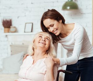 Junge Frau kümmert sich um ältere Dame im Rollstuhl