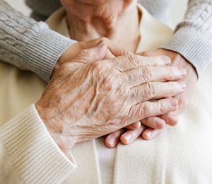 Am Foto sind Hände von zwei Personen zu sehen welche sich gegenseitig halten. Eine Hand ist von einer älteren Frau die zweite Hand ist von der Betreuerin.