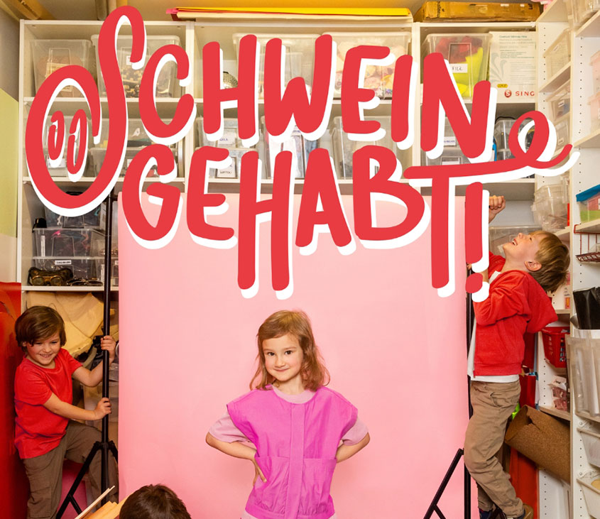 Am Foto sind vier Kinder, davon ein Mädchen und der Schriftzug Schwein gehabt zu sehen.