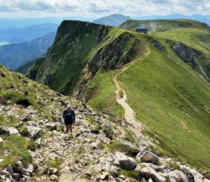 Am Bild ist eine Frau beim Wandern auf einem Bergkamm zu sehen.
