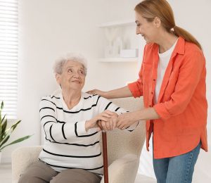 Am Foto ist eine alte Frau mit ihrer Pflegerin zu sehen. Die Dame hat einen Gehstock zur Unterstützung.