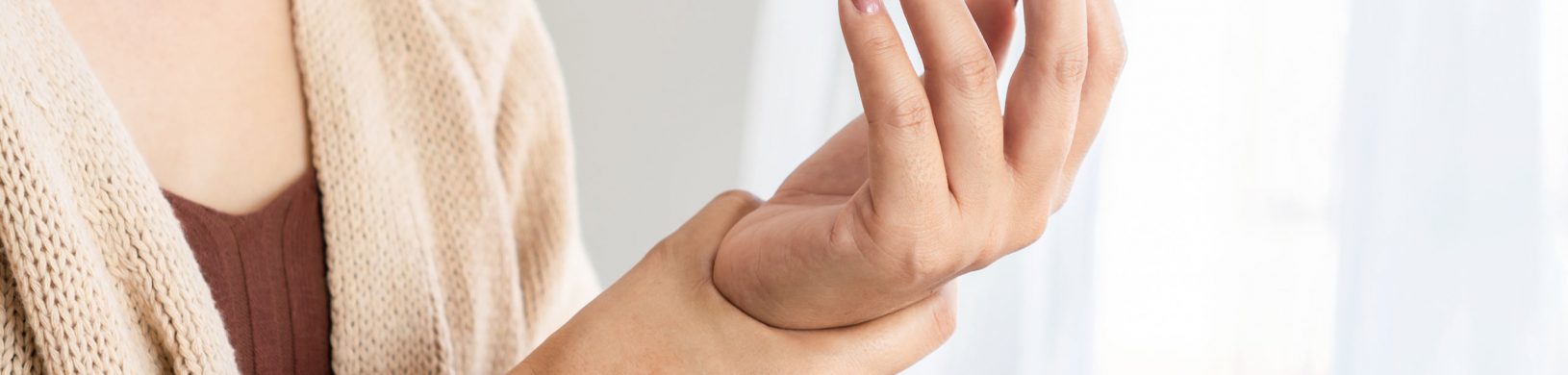 Am Foto sieht man eine Frau die ihre schmerzende Hand hält